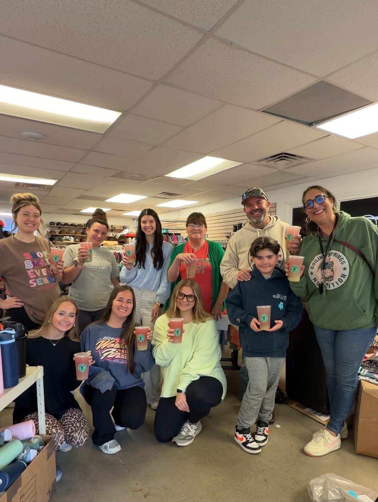 A group of BSN neighbors and staff posing together inside the shop, each holding a BSN drink